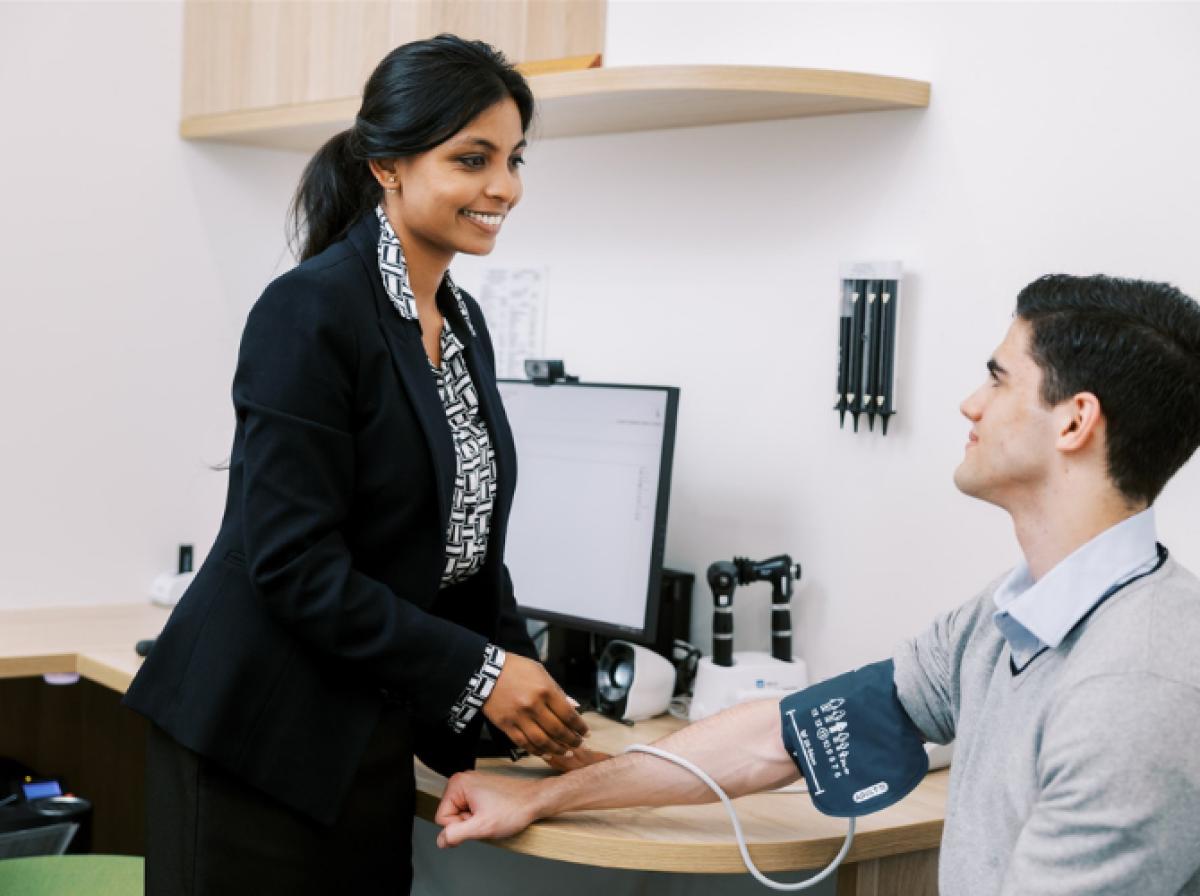 Female doctor taking a male patient’s blood pressure in a medical consultation room